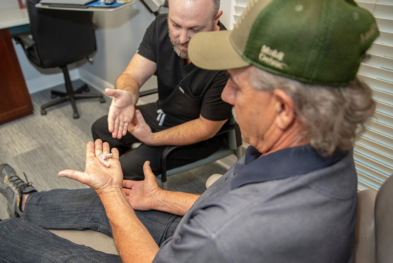 Patient examining dental implant model within the dental office